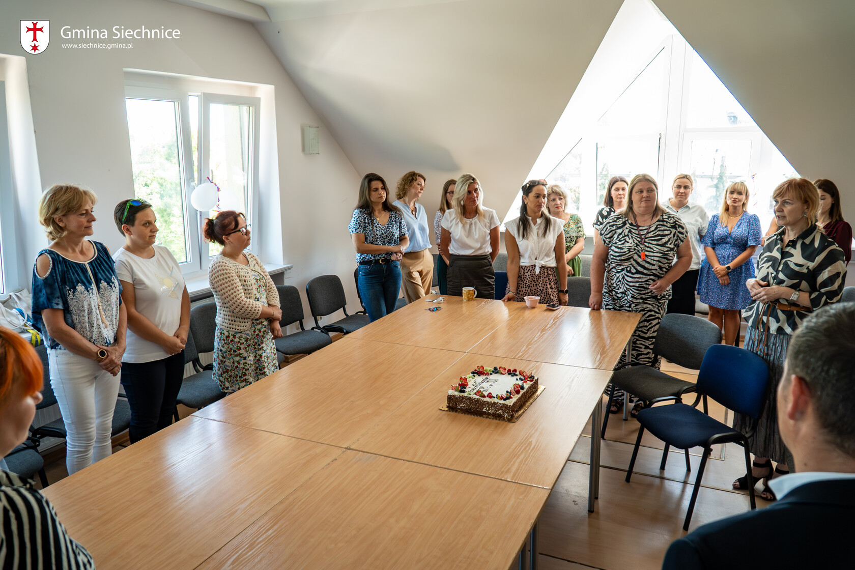 Pracownicy CUS zgromadzili się w sali wokół stołu. Na stole symboliczny tort z okazji utworzenia CUS