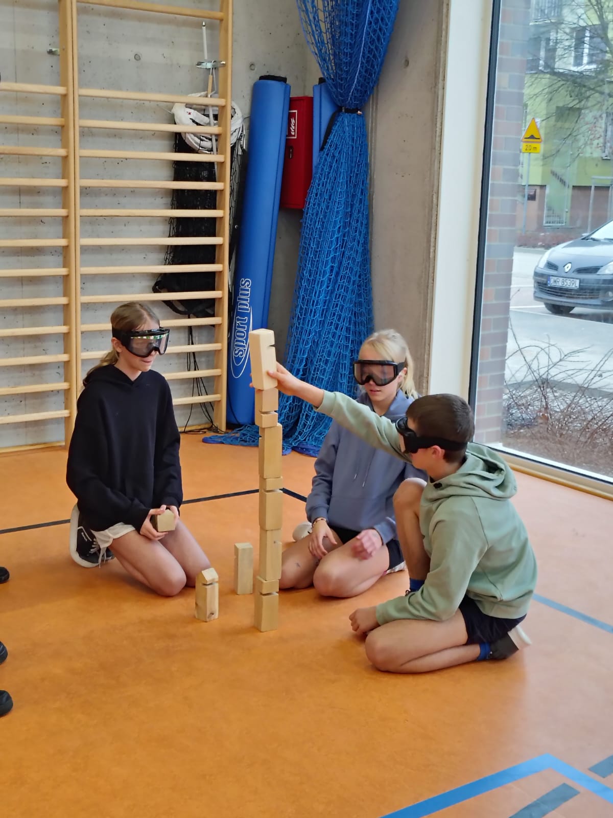 Młodzież w alkogoglach buduje wieżę z klocków w trakcie zajęć profilaktycznych.