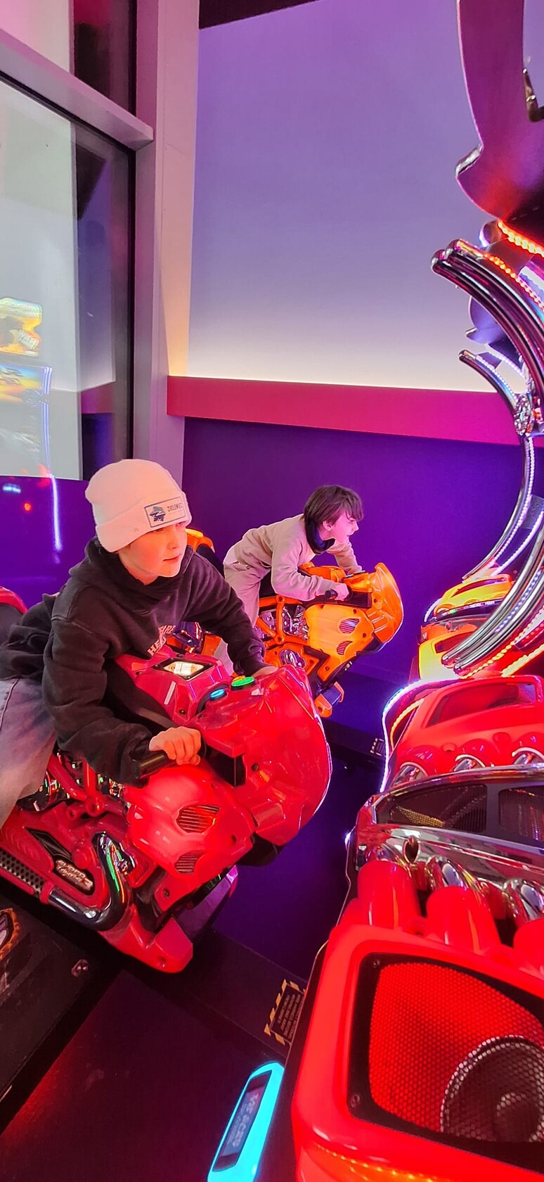 Młodzież na symulatorach wyścigów motocyklowych.